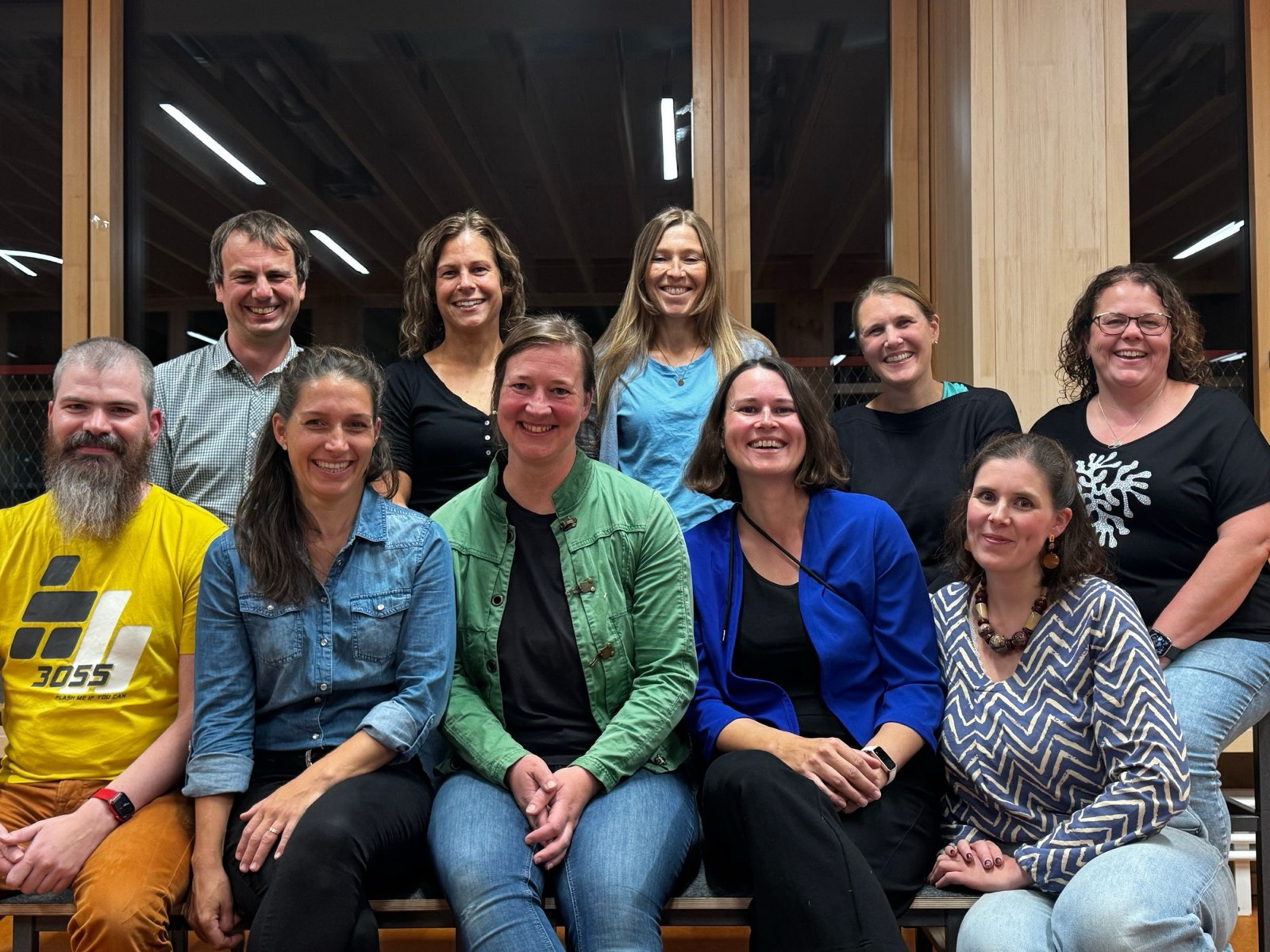 Gruppenfoto des Elternbeirats 2026–2028 der Grundschule Ost: zehn lächelnde Eltern sitzen und stehen in zwei Reihen vor großen Holzfenstern.